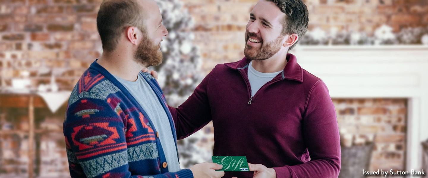Two men smiling and holding a gift card.